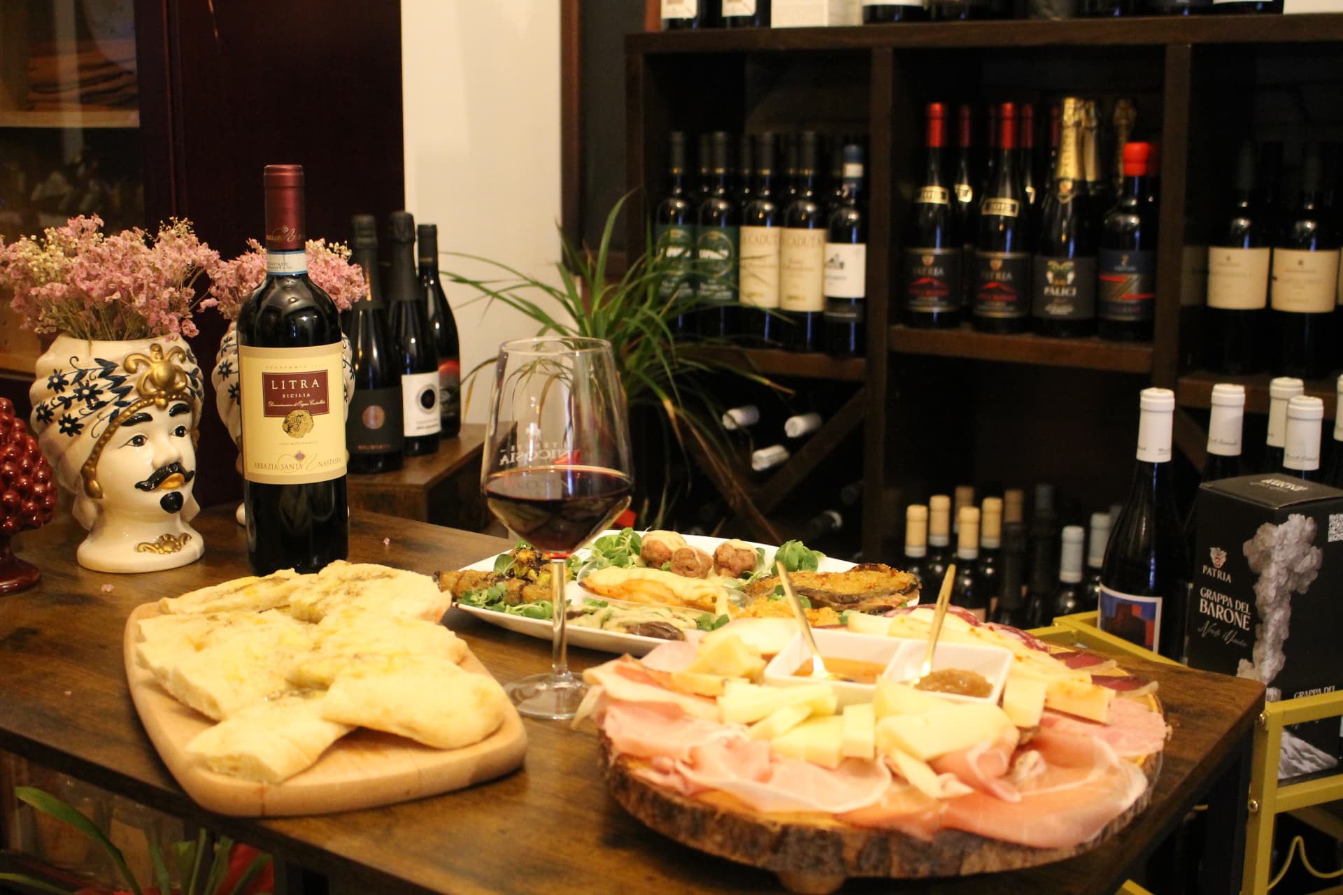 Tagliere di salumi e formaggi siciliani con un calice di vino rosso
